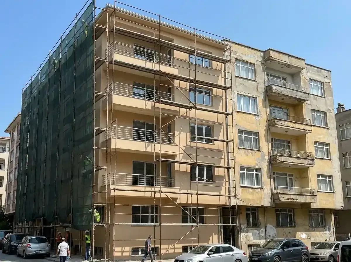Yarısı iskeleyle kaplı, yarısı eski sıvasıyla duran altı katlı apartman cephesi
